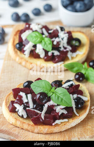 Bruschetta mit gebackenen Rüben, Blaubeeren, FETA-Käse, Basilikum und Balsamico. Gourmet Snack. Gesunde Ernährung. Selektiver Fokus Stockfoto