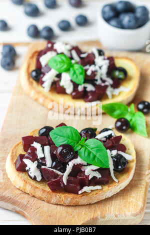 Bruschetta mit gebackenen Rüben, Blaubeeren, FETA-Käse, Basilikum und Balsamico. Gourmet Snack. Gesunde Ernährung. Selektiver Fokus Stockfoto