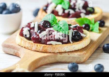 Bruschetta mit gebackenen Rüben, Blaubeeren, FETA-Käse, Basilikum und Balsamico. Gourmet Snack. Gesunde Ernährung. Selektiver Fokus Stockfoto