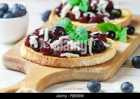 Bruschetta mit gebackenen Rüben, Blaubeeren, FETA-Käse, Basilikum und Balsamico. Gourmet Snack. Gesunde Ernährung. Selektiver Fokus Stockfoto