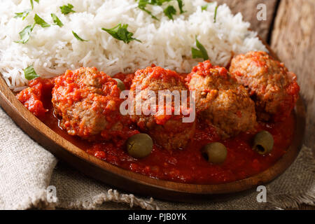 Gebackene Fleischbällchen in pikanter Tomatensauce serviert mit Reis close-up auf einem Teller auf dem Tisch. Horizontale Stockfoto