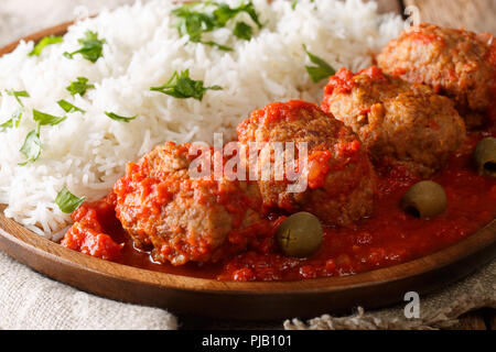 Traditionelle Soutzoukakia Rezept (Griechisch gebackene Hackfleischbällchen in Tomatensauce) mit Beilage von Reis close-up auf einem Teller. Horizontale Stockfoto