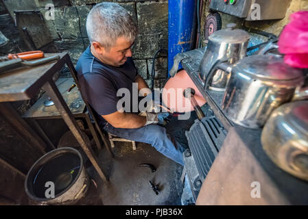 Unbekannter mann Reparaturen defekter Teekessel in einem kleinen Laden mit einem reparierten Kessel im Vordergrund in Sanliurfa Türkei. vom 19. Juli 2018 Stockfoto