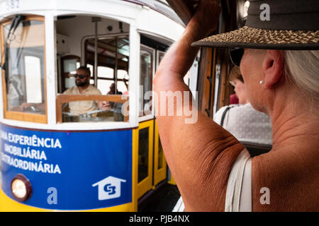 Frau gekleidet in weiss mit Stroh Hut auf eine Straßenbahn in Lissabon Stockfoto
