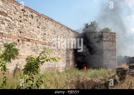 Ein Feuer und Rauch in der Nähe der Ruinen der Mauern von Konstantinopel. (Heute Istanbul in der Türkei) Stockfoto
