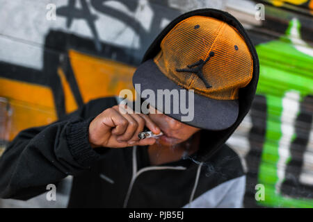 Eine mexikanische Anhänger von Santa Muerte (Heilige Tod) Marihuana raucht eine Zigarette während einer Pilgerreise in Tepito, Mexiko City, Mexiko. Stockfoto