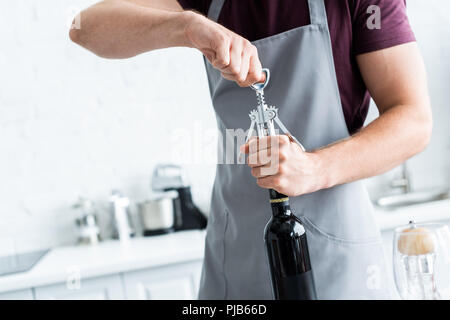 7/8 Schuß des Menschen in der Schürze öffnen Flasche Wein Stockfoto