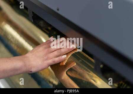 Große professionelle Drucker, Verarbeitung einer großen Skala Glänzend vinyl Roll. Stockfoto