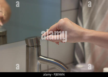 Das Mädchen öffnet das Metall Hahn für die Hände waschen Stockfoto