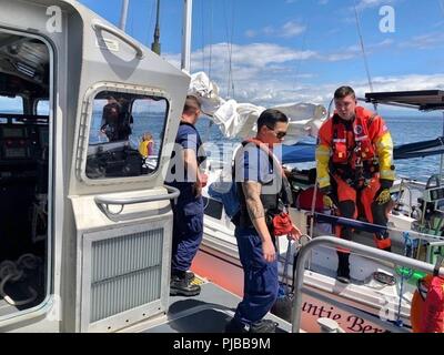 Unteroffiziere 3. Klasse Jordanien Harlacher und Matthew Boyd, beide 45-Fuß-Antwort Boat-Medium Besatzungsmitglieder, von Station Bellingham, bereiten Sie eine verletzte Frau, ein Segelschiff, das auf Grund der Nähe Sucia Island mit Hilfe einer Luftfahrt überleben Techniker der Air Station Port Angeles, 2. Juli 2018 lief zu übertragen. Die verletzte Frau, die angeblich habe Platzwunden und eine Rippe Verletzung während des Unfalls. Us-Küstenwache Stockfoto