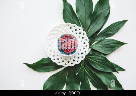 Eine Tasse mit verschiedenen Beeren gefüllt steht auf grünen Blättern. Konzept der gesunden Ernährung oder Diät. Stockfoto