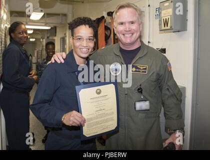 NORFOLK, Virginia (9. Juli 2018) Hospital Corpsman 3. Klasse Deja Smith, von Hartford, Connecticut, auf USS Gerald R. Ford's (CVN 78) Medizinische Abteilung zugewiesen, erhält Ihre Bescheinigung über die Bestellung, die in den Rang eines Petty Officer third Class von Kapitän Richard McCormack, Ford's kommandierender Offizier. Smith war nach ihrer Auswahl für die verdienstvolle Förderung Programm gefördert. Stockfoto