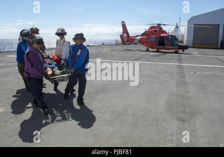 Pazifik (11. Juli 2018) Segler zugeordnet zu militärischen Sealift Command Hospital Ship USNS Mercy (T-AH 19), erhalten Sie einen Patienten von einem U.S. Coast Guard MH-65 Dolphin Hubschrauber für die Übertragung zu einer chemischen Dekontamination Zimmer, bevor Sie bei der Suche und Rettung, und chemischen Dekontamination Übung zur Unterstützung der Rand des Pazifik (Rimpac), Juli 11. 25 Nationen, 46 Schiffe und fünf U-Boote, über 200 Flugzeuge, und 25.000 Mitarbeiter beteiligen sich an Rimpac vom 27. Juni bis 2. August in und um die hawaiischen Inseln und Südkalifornien. Die weltweit größte Internatio Stockfoto