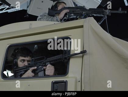 Us Air Force Staff Sgt. Matthäus Schmidt (links unten) und Airman 1st Class Chas Leimuller (oben rechts), abwehren einer terroristischen Fahrzeug während einer virtuellen Realität Humvee Konvoi Mission in einer Neukonfiguration Fahrzeug Tactical Trainer (RVTT) am Joint Base Elmendorf-Richardson, Ala., 11. Juli 2018. Die Flieger, die beide aus der Sicherheitskräfte Geschwader mit Die 128 Luftbetankung Flügel, Wisconsin Air National Guard, die in der Simulation teilnehmenden als Teil ihres Landes Navigation Kurs während der Einheit waren 15 Tage Training Mission in Alaska. (Air National Guard Stockfoto