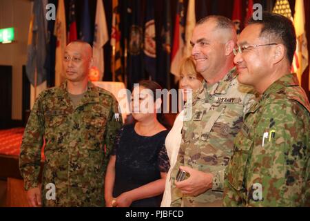 Ausgehende U.S. Army Garrison Japan Command Sgt. Große Holland, und seine Frau, Wendy, posieren Sie mit japanischen Gäste nach Holland Abgabe der Verantwortung Zeremonie Juli 11, 2018, im Camp Zama Gemeinschaft Club. Holland erzählte die Versammelten, die usag Japan die beste Zuordnung war von seiner 32-jährigen Karriere in der Armee. Stockfoto