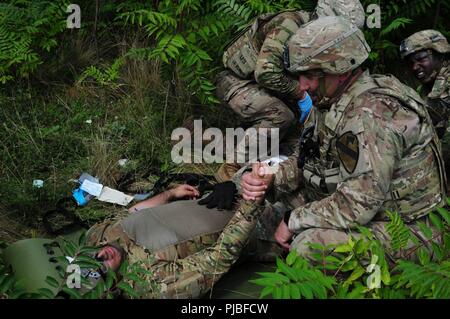 Army Staff Sgt. Jordan Murzyn an den Spähtrupp, Sitz und die Konzernzentrale, 2nd Battalion, 5th Cavalry Regiment, 1st Armored Brigade Combat Team, 1.Kavallerie Division Konsolen Armee Pvt. 1. Klasse Eric Martinez zu den Spähtrupp, HHC, 2-5 Cav, 1 ABCT, 1 CD aufgrund einer simulierten Verletzungen am Mihail Kogalniceanu Airbase in Rumänien, 10. Juli 2018 zugewiesen. Soldaten führte eine Air Assault Training zur Unterstützung der Atlantischen lösen, ein bleibendes Training übung zwischen der NATO und der US-Streitkräfte. Stockfoto