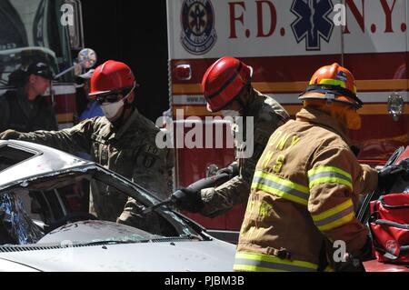 Edwin Hernandez, ein rettungssanitäter/Instrukteur, Haz-Mat Operationen, Feuerwehr der Stadt New York (FDNY) beobachtet, wie der US-Army Reserve Spc Aldrich Cushnie mit der 468Th Engineer Detachment (Brandbekämpfung Hauptsitz), 368 Techniker Bataillon, 302d Manöver Verbesserung Brigade, 412 Theater Ingenieur Befehl in Danvers, Massachusetts, verwendet eine Stichsäge der A-Säule eines Fahrzeugs während einer aus verunfallten Fahrzeugen im New York City der chemischen, biologischen, radiologischen und nuklearen (CBRN) Gemeinsame Ausbildung Übung (JTE) am Times Square Church in New York City, New Y Stockfoto