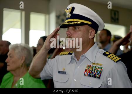 Kapitän Rob McLellan, der kommandierende Offizier der Küstenwache Sektor Mobile, Alabama, begrüßt den nationalen Ensign bei einem Befehl Zeremonie in Pascagoula, Mississippi, 11. Juli 2018. Während der Zeremonie, Kapitän Travis L. Carter erleichtert Kapitän Christopher S. Webb als der kommandierende Offizier des Projekts Außenstelle Gulf Coast. Stockfoto