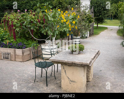 Steintisch mit Blumen und Stühle im Garten, Steinboden Stockfoto