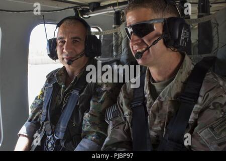 Gen. Chiya, Kommandant der syrischen Demokratischen Kräfte in Syrien naher Fluss Euphrat Valley, Aktien eine unbeschwerte Gespräch über Headset mit US-Armee Generalmajor James B. Jarrard, Kommandeur der Special Operations Joint Task Force-Operation inhärenten lösen, wie Sie über Syrien in eine UH-60 Blackhawk, 11. Juli 2018 flog. Die Koalition Generäle met mit Gen. Chiya der Fortschritt der Operation Roundup zu diskutieren. Stockfoto