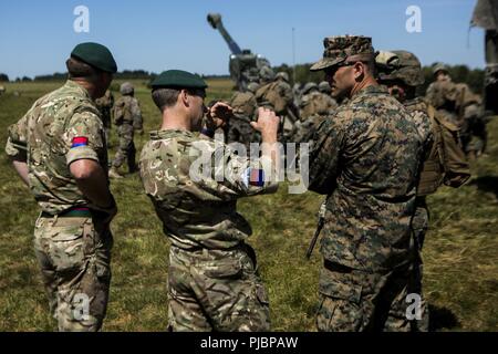 Us Marine Corps Kapitän James Ayule, der kommandierende Offizier der Echo-Akku, 2. Bataillon, 10 Marine Regiment (2/10), 2nd Marine Division, bespricht die M777 Haubitze mit britischen Armee Commando Oberstleutnant Mark Dornan, Mitte, regimental Commander, und der Britischen Armee Commando Sgt. Maj. Malcom Shaw, Links, regimental Sergeant Major, beide mit 29 Commando Regiment, in Salisbury, England, Juli 2, 2018. Marines mit der Unit durchgeführt live-fire Übungen mithilfe der M777 Haubitze während der Übung grüne Kanone 18. Grüne Kanone ist eine multinationale Übung mit US-Marines die Gelegenheit, t Stockfoto