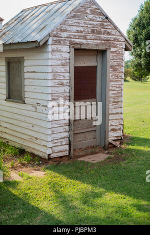 Ein altes verwittertes Holz- Werkzeug mit abblätternder Farbe und ein Blechdach auf einem ländlichen Bauernhof in Oklahoma, USA. Stockfoto