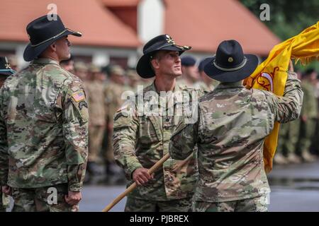 Oberstleutnant Adam Lakai (Mitte), ausgehende Commander für Battle Group Polen, übergibt die REGIMENTAL Farben zu Oberst Patrick Ellis (rechts), 2.Kavallerie Regimentskommandeur, während eine Änderung der Befehl Zeremonie für die Battle Group Polen Bemowo Piskie, Polen am 14. Juli 2018. Battle Group Polen ist ein einzigartiges, multinationale Koalition von USA, Großbritannien, Kroatischen und rumänischen Soldaten, die mit der polnischen 15 mechanisierte Brigade als Abschreckung Kraft zur Unterstützung des NATO-Enhanced vorwärts Präsenz dienen. Stockfoto