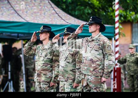 (Von links) Oberstleutnant Adam Lakai, Oberst Patrick Ellis, und Oberstleutnant Timothy Wright salute bei einem Befehl Zeremonie für die Battle Group Polen Bemowo Piskie, Polen am 14. Juli 2018. Battle Group Polen ist ein einzigartiges, multinationale Koalition von USA, Großbritannien, Kroatischen und rumänischen Soldaten, die mit der polnischen 15 mechanisierte Brigade als Abschreckung Kraft zur Unterstützung des NATO-Enhanced vorwärts Präsenz dienen. Stockfoto