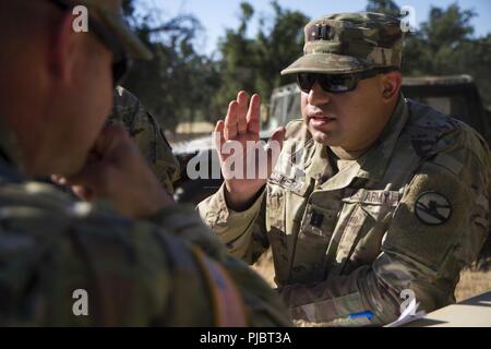 FORT HUNTER LIGGETT - US Army Reserve Kapitän Steven Cabrera Der 1-417., 91st Operationen Brigade, Charlie Company diskutiert die Einrichtung eines simulierten Improvised Explosive Device Ausbildung Lane während der 91St Abteilung Weiterbildung unterstützen Training Übung (CSTX), 12. Juli 2018 in Ft. Hunter Liggett, Kalifornien. CSTX 91-18-01, die sicherstellt, dass America's Army Reserve Einheiten und Soldaten ausgebildet und zum Einsatz bereit und fähig, Bekämpfung bereit, und tödlichen Feuerkraft zur Unterstützung der Armee und unsere gemeinsamen Partner überall in der Welt. Stockfoto