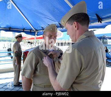 GROTON, Anschl. (13 Juli 2018) Commander, Submarine Squadron 4, Kapitän Gehirn Sittlow Pins den Befehl auf See Pin auf Cmdr. Thomas Niebel während einer Aufladung der Befehl Zeremonie am Freitag, den 13. Juli 2018 an Bord der historischen Schiff USS Nautilus (SSN-571) in Groton Anschl. Die Zeremonie ist eine altehrwürdige Veranstaltung offiziell erteilt Behörde Niebel Befehl die Pre-Commissioning Steuergerät (PCU) G. Hyman Rickover (PCU-795). Niebel wird der erste Kommandant werden auf Befehl der Rickover. Stockfoto