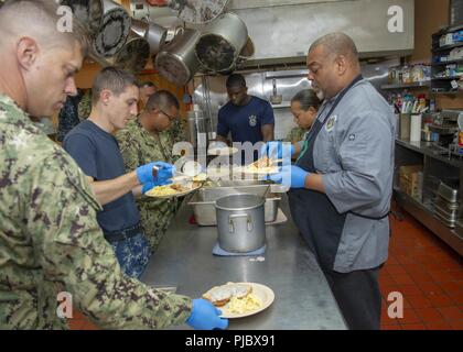 (3. Juli 2018) Segler der Nimitz-Klasse Flugzeugträger USS George Washington (CVN 73) und Jody Gholson (rechts), die Küche der Halbinsel Rescue Mission Mahlzeiten vorbereiten, während die ehrenamtliche Mitarbeit in der Halbinsel Rescue Mission in Newport News. George Washington wird gerade Tanken komplexe Überholung (RCOH) bei Newport News Werft. RCOH ist ein fast 4-jährigen Projekt nur einmal während einer Fluggesellschaft, die 50-jährige Nutzungsdauer, einschließlich Betankung von zwei nukleare Reaktoren des Schiffes sowie erhebliche Reparaturen, Upgrades und Modernisierung. Stockfoto