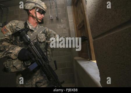 Ein U.S. Army National Guard M249 Gunner aus Bravo Company, 1.BATAILLON, 114 Infanterie (Air Assault) sucht ein Gebäude während eines Air Assault Training Mission auf Joint Base Mc Guire-Dix - Lakehurst, New Jersey, 16. Juli 2018. Stockfoto