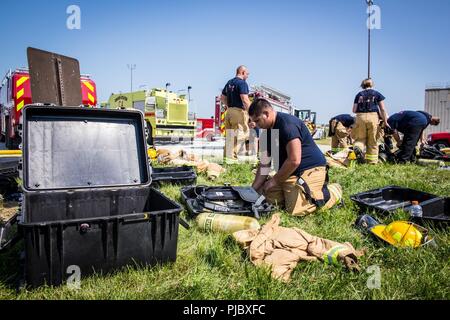 Feuerwehrmänner zugewiesen, um die 139 Feuerwehr Notdienste, Missouri Air National Guard, ihre zahnradsatz nach einem Kampf mit der simulierten Flugzeugen Feuer in der Offutt Air Force Base, Neb., 16. Juli 2018. Die Zivilisten und Flieger waren die Durchführung einer Flugzeuge live-fire Übung als Teil ihrer jährlichen Schulung. Stockfoto