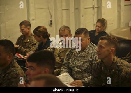 Der chilenischen Marine Kapitän Jorge Keitel, Links, ein Sonderberater mit speziellen Zweck Marine Air-Ground Task Force - Southern Command, hört zu, wie die US-Marine Maj Thomas Granat, die Kommunikation der Strategie und Operations Officer mit dem SPMAGTF-SC, während eines simulierten Naturkatastrophe bohren an Bord der USS Gunston Hall (LSD 44), 13. Juli 2018. In einem historischen ersten, SPMAGTF-SC Keitel und der Kolumbianischen Marine Infanterie Oberstleutnant Erick Del Rio in den Mitarbeitern der Einheit integriert ist. Die Marinesoldaten und Matrosen von SPMAGTF - SC sind die Zusammenarbeit im Bereich Sicherheit Training und Engineering Projekte neben Partner Stockfoto