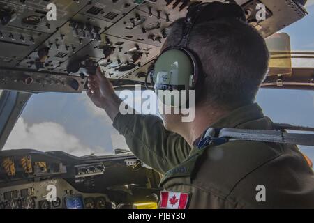 Pazifik (15. Juli 2018) Royal Canadian Air Force Corporal David Bettle, Flight Engineer mit einer kanadischen Aurora (CP 140) Flugzeuge, passt Bedienelemente im Cockpit während des Fluges als Teil eines sub-jagd Szenario während der Rand des Pazifik (Rimpac) Übung. 25 Nationen, 46 Schiffe, 5 U-Boote, über 200 Flugzeuge und 25.000 Angestellte beteiligen sich an Rimpac vom 27. Juni bis 2. August in und um die hawaiischen Inseln und Südkalifornien. Die weltweit größte internationale maritime Übung RIMPAC bietet eine einzigartige Ausbildung während der Förderung und Erhaltung der Coop Stockfoto