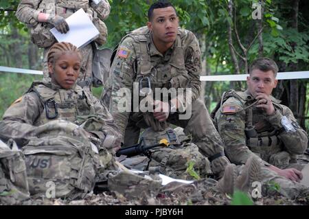 1. Lt Zachary Bregovi (rechts), zu 18 Military Police Brigade, Sgt. Xavier Perkins (Mitte), Zu 16. sustainment Brigade, Sgt. Shuntaneque Greenwald (links), der US-amerikanischen Armee NATO-Brigade zugewiesen werden, hören eine situationsbezogene Übung Lane kurz während der 2018 21 Theater Sustainment Command besten Krieger Wettbewerb Juli 10, 2018 in Baumholder, Deutschland. Während der Übung, Konkurrenten navigiert ein Improvised Explosive Device Segment, in der Lage sein, verschiedene Munition zu identifizieren, bounding Techniken über 100 Meter, und die Interaktion mit Medien Personal demonstrieren. #21 BWC 18 # FirstInSup Stockfoto