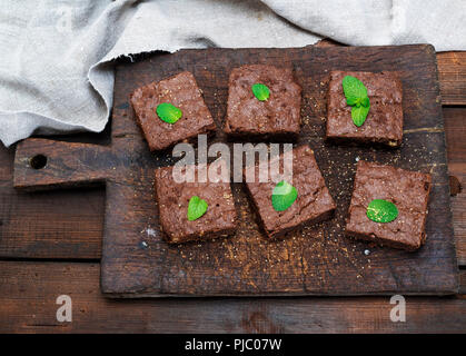 Gebackene quadratische Stücke von Brownie brownie Torte auf einem alten braun Holz Schneidebrett, Ansicht von oben Stockfoto