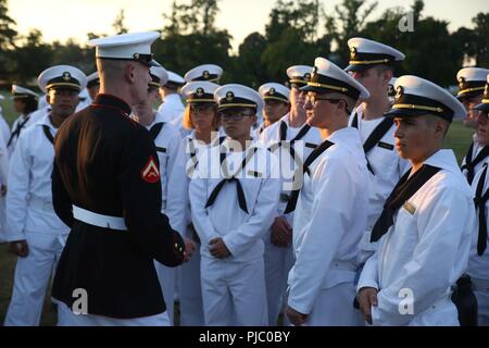 Ein Marine mit dem US Marine Corps leise Bohren Platoon spricht mit Midshipmen Teilnahme an der Plebe Sommer BCD-Leistung an der United States Naval Academy, Annapolis, MD., Juli, 19, 2018. Plebe Sommer ist eine Ausbildung, die Übergänge, die Zivilbevölkerung zu Midshipmen, und ist eine Voraussetzung für alle ankommenden Neulingen der USNA. Die jährliche Schlacht Farbe Zeremonie gibt die Midshipmen die Möglichkeit, die Beziehung zwischen der Navy und Marine Corps zu erleben. Stockfoto