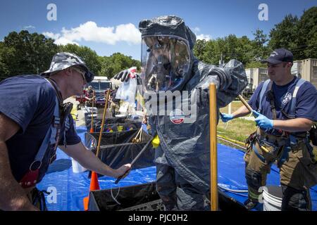 Us-Armee Umfrage Teammitglied Staff Sgt. Nicky Lam, 21 Massenvernichtungswaffen Destruction-Civil Support Team (21 WMD-CST), New Jersey der National Guard, wird von Morris Township Feuerwehrmänner während eine interinstitutionelle Koordinierung an die Heimatverteidigung Technology Center, Picatinny Arsenal, N.J., 18. Juli 2018 dekontaminiert werden. Das 21 WMD-CST mit den New-jersey Army National Guard's 1 150 Angriff Hubschrauber Bataillon ausgebildet; die New Jersey Abteilung von Korrekturen C.O.B.R.A. (Chemische, Kampfmittel, biologische, radiologische, Beihilfen), Picatinny Arsenal Feuerwehr, New Jersey Emergen Stockfoto