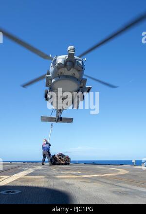 Philippinischen MEER (20 Juli 2018) Segler, die ticonderoga-Klasse geführte-missile Cruiser USS Antietam (CG54) bereiten Sie eine Ladung an einem MH-60R Sea Hawk Hubschrauber, Die "Warlords" von Hubschrauber Maritime Strike Squadron (HSM) 51 zugeordnet, da sie über dem Schiff Flight Deck schwebt. Antietam freut - in den USA 7 Flotte Bereich für Maßnahmen zur Erhöhung der Sicherheit und Stabilität in der indopazifischen Region bereitgestellt. Stockfoto