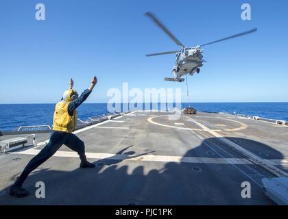 Philippinischen MEER (20. Juli 2018) Der Bootsmann Mate 3. Klasse Aaron Mason, von Lafayette, Indiana, Signale zu einem MH-60R Sea Hawk Hubschrauber, der "Warlords" von Hubschrauber Maritime Strike Squadron (HSM) 51 zugeordnet, da sie schwebt über dem Flight Deck der Ticonderoga-Klasse geführte-missile Cruiser USS Antietam (CG54). Antietam freut - in den USA 7 Flotte Bereich für Maßnahmen zur Erhöhung der Sicherheit und Stabilität in der indopazifischen Region bereitgestellt. Stockfoto