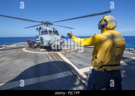 Philippinischen MEER (20. Juli 2018) Der Bootsmann Mate 1. Klasse Kenneth Haley, aus Katy, Texas, Signale zu einem MH-60R Sea Hawk Hubschrauber, der "Warlords" von Hubschrauber Maritime Strike Squadron (HSM) 51, während eines Fluges viertel Evolution auf der Ticonderoga-Klasse geführte-missile Cruiser USS Antietam (CG54) zugeordnet. Antietam freut - in den USA 7 Flotte Bereich für Maßnahmen zur Erhöhung der Sicherheit und Stabilität in der indopazifischen Region bereitgestellt. Stockfoto