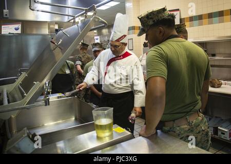 Stephen Dziedzic strahlt, Küchenchef, Sodexo, beauftragt Marines in kaltes Essen Vorbereitung bei Mess Hall 128, Camp Lejeune, N.C., 11. Juli 2018. Die Fortbildung vermittelt Methoden zur Marine food service Spezialisten die grundlegenden Dienstleistungen, Backen, Braten, zu verbessern, Rezeptur, kaltes Essen Zubereitung und Grillen. Stockfoto