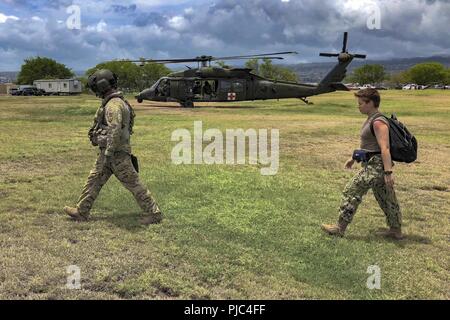 JOINT BASE Pearl Harbor - HICKAM, Hawaii (Juli 13, 2018) ein Soldat von der US-Armee Bravo Company, 2-25 Aviation Regiment, 25 Combat Aviation Brigade führt ein Patient - Schauspieler zu einem Hubschrauber für eine medizinische Evakuierung Juli 13, als Teil des Pacific Rim (Rimpac) Übung. 25 Nationen, 46 Schiffe, 5 U-Boote, über 200 Flugzeuge und 25.000 Angestellte beteiligen sich an Rimpac vom 27. Juni bis 2. August in und um die hawaiischen Inseln und Südkalifornien. Die weltweit größte internationale maritime Übung RIMPAC bietet eine einzigartige Ausbildung bei gleichzeitiger Förderung einer Stockfoto