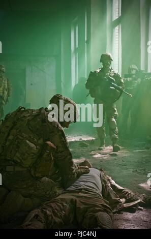 Yavoriv, Ukraine-Klasse 703-2018 Basic Führung Kurs von 7th Army Training Befehl nicht angewiesen, Unteroffizieren während ein Feld Training am Yavoriv Combat Training Center (CTC) am 11. Juli. 40 Soldaten der 27 Infantry Brigade Combat Team (Vorwärts) Teil im Kurs und wie hier gesehen, Sgt. Robert Majewski von West Seneca, NY, reagiert auf einen Unfall, Situation und truppführer Sgt. Chris Cormack von Penfield, NY, inspiziert die Verteidigungslinie beim Empfang Kontakt aus Aufständische in einem städtischen Schulungsumgebung. Stockfoto