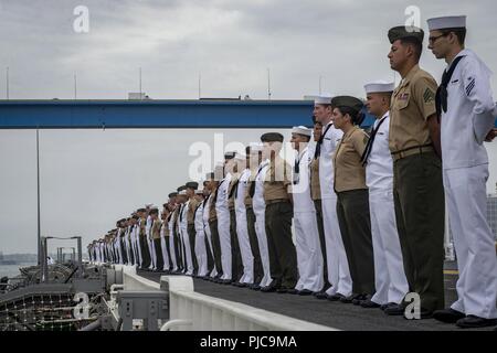 Freigegeben PAZIFISCHER OZEAN (10 Juli 2018) - Segler zugeordnet Wasp-Klasse amphibisches Schiff USS Essex (LL 2) und Marines zugeordnet. bis 13 Marine Expeditionary Unit (MEU) die Schienen Mann auf dem Flight Deck während der Abfahrt Marinestützpunkt San Diego während einer planmäßigen Einsatz von Essex Amphibious Ready Group (ARG) und 13 MEU. Das Essex ARG/MEU Team ist ein stark, flexibel, reaktionsschnell und gleichbleibende Kraft in der Lage, Manöver Kriegsführung in allen Domänen; es ist ausgestattet und skalierbar auf jede Krise von der humanitären Hilfe und Katastrophenhilfe zu Blindbewerbungen zu reagieren. Stockfoto