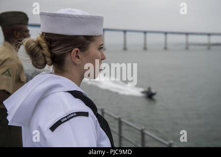 Freigegeben PAZIFISCHER OZEAN (10 Juli 2018) - der Luftfahrt Bootsmann Mate (Kraftstoff) Airman Londyn Soileau, zugeordnet zu den Wasp-Klasse amphibisches Schiff USS Essex (LL 2), bemannt die Schienen während der Abfahrt Marinestützpunkt San Diego während einer planmäßigen Einsatz von Essex Amphibious Ready Group (ARG) und 13th Marine Expeditionary Unit (MEU). Das Essex ARG/MEU Team ist ein stark, flexibel, reaktionsschnell und gleichbleibende Kraft in der Lage, Manöver Kriegsführung in allen Domänen; es ist ausgestattet und skalierbar auf jede Krise von der humanitären Hilfe und Katastrophenhilfe zu Blindbewerbungen zu reagieren. Stockfoto