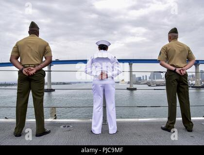 Freigegeben PAZIFISCHER OZEAN (10 Juli 2018) - Segler zugeordnet Wasp-Klasse amphibisches Schiff USS Essex (LL 2) und Marines zugeordnet. bis 13 Marine Expeditionary Unit (MEU) die Schienen Mann auf dem Flight Deck während der Abfahrt Marinestützpunkt San Diego während einer planmäßigen Einsatz von Essex Amphibious Ready Group (ARG) und 13 MEU. Das Essex ARG/MEU Team ist ein stark, flexibel, reaktionsschnell und gleichbleibende Kraft in der Lage, Manöver Kriegsführung in allen Domänen; es ist ausgestattet und skalierbar auf jede Krise von der humanitären Hilfe und Katastrophenhilfe zu Blindbewerbungen zu reagieren. Stockfoto