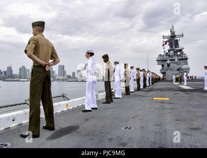 Freigegeben PAZIFISCHER OZEAN (10 Juli 2018) - Segler zugeordnet Wasp-Klasse amphibisches Schiff USS Essex (LL 2) und Marines zugeordnet. bis 13 Marine Expeditionary Unit (MEU) die Schienen Mann auf dem Flight Deck während der Abfahrt Marinestützpunkt San Diego während einer planmäßigen Einsatz von Essex Amphibious Ready Group (ARG) und 13 MEU. Das Essex ARG/MEU Team ist ein stark, flexibel, reaktionsschnell und gleichbleibende Kraft in der Lage, Manöver Kriegsführung in allen Domänen; es ist ausgestattet und skalierbar auf jede Krise von der humanitären Hilfe und Katastrophenhilfe zu Blindbewerbungen zu reagieren. Stockfoto