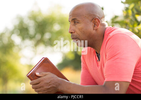 African American man beten und tief in Gedanken. Stockfoto